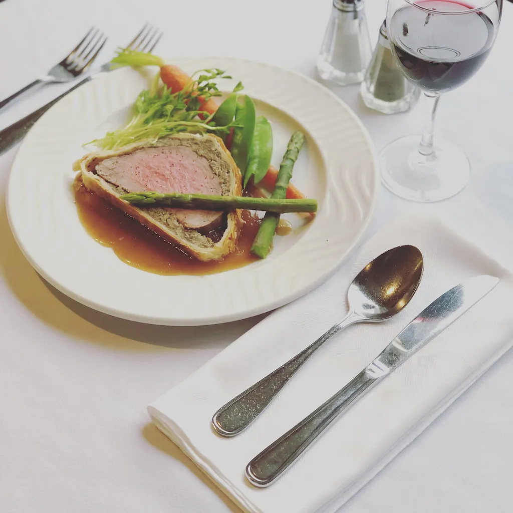 photo of a slice of beef wellington sitting on a dinner plate